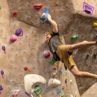 Advanced finalist leaping for a rock with feet flying sideways